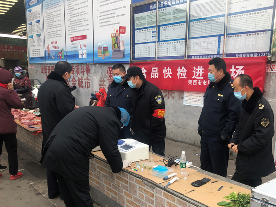 在农贸市场莱西市市场监督管理局工作人员正在对蔬菜进行快速检测