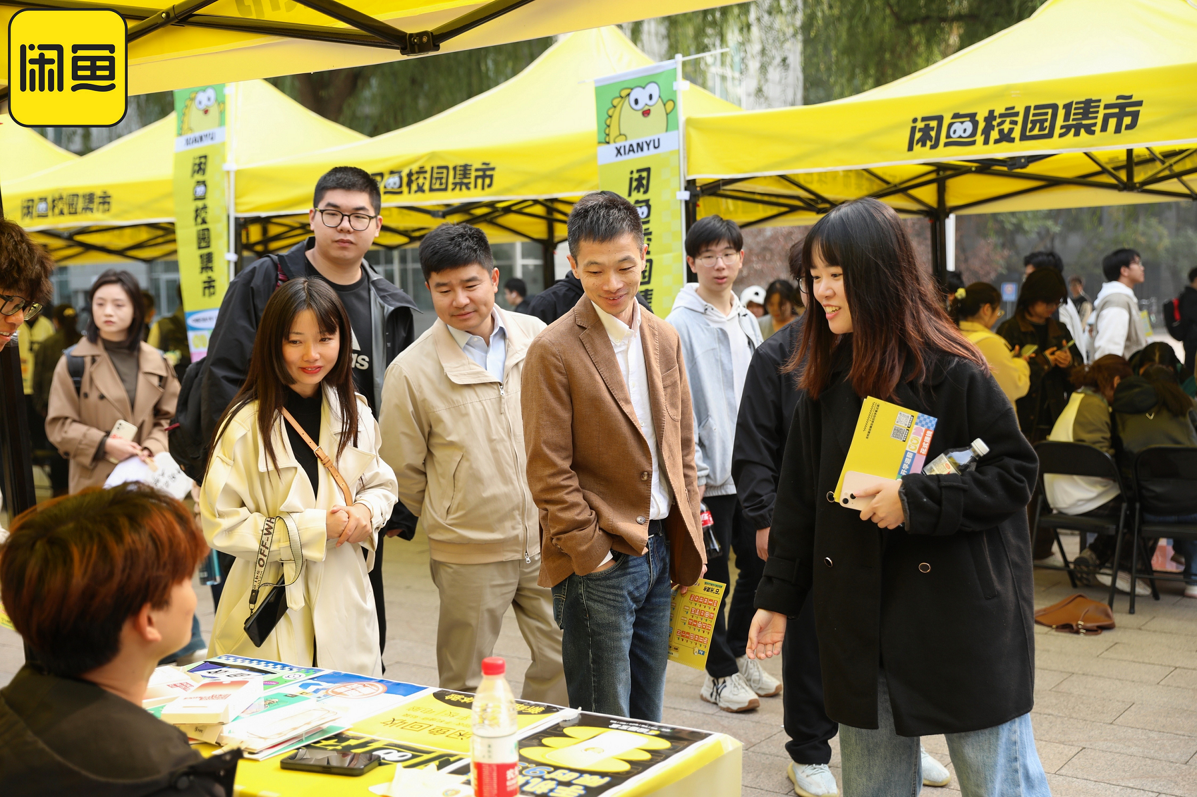 （闲鱼总裁丁健在校园集市现场与学生交流其带来的特色物品）